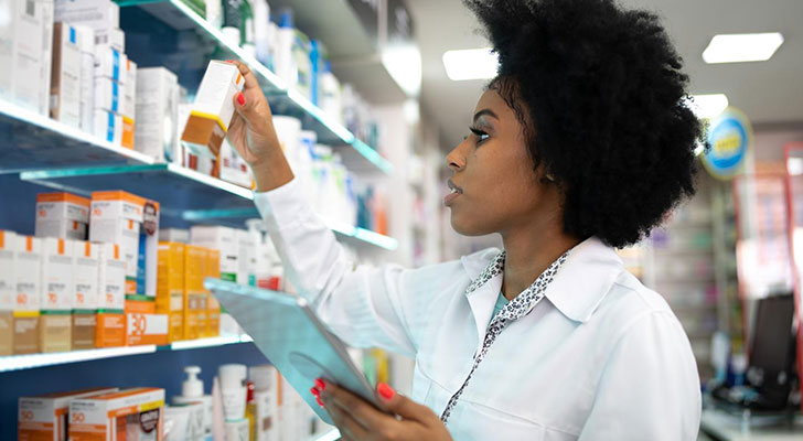 Pharmacist examining shelves of medicine.