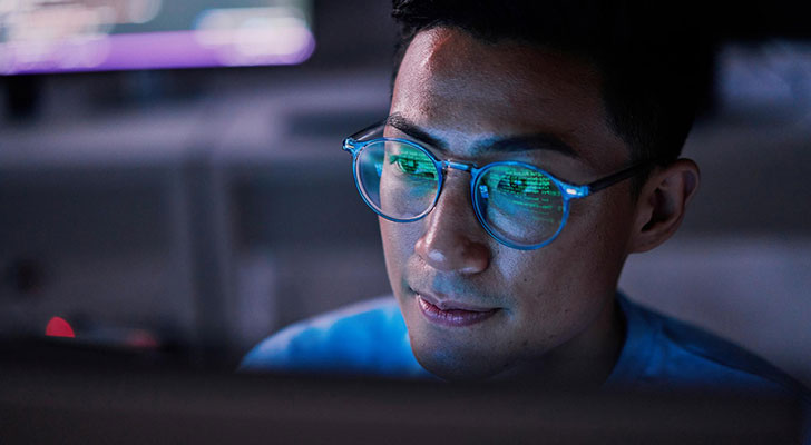 Person wearing glasses while working on a monitor.